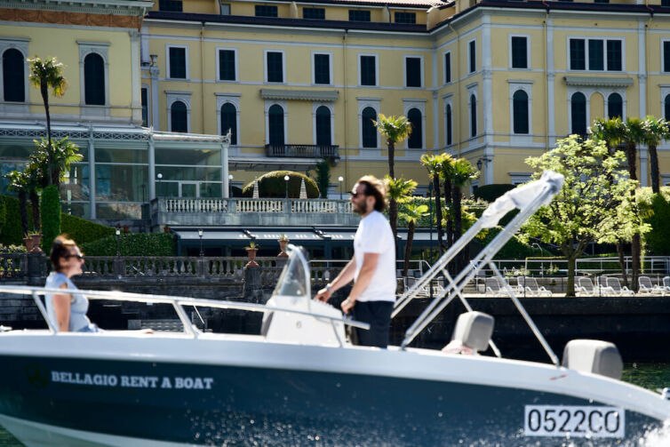Boat rental with a couple surfing in front of the Grand Hotel Villa Serbelloni